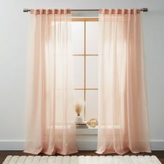 a window with sheer curtains and a rug on the floor