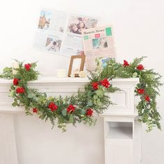 a fireplace decorated with greenery and red flowers