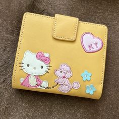 a hello kitty wallet with flowers and hearts on the front, sitting on a fur surface