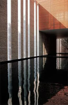 an empty pool in front of a building with vertical blinds on the wall and floor