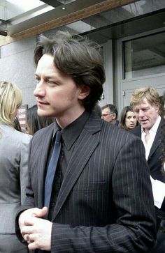 a man in a suit and tie standing next to other people