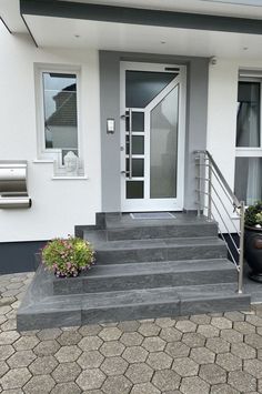 a white house with steps leading to the front door and flower pots on the side