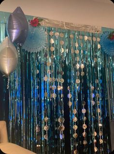 balloons and streamers are hanging from the ceiling in front of a curtain with blue lights