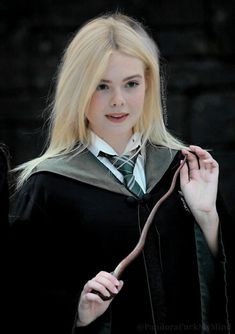 a woman with blonde hair wearing a harry potter costume and holding a wand in her hand