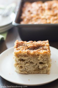 a piece of cake sitting on top of a white plate next to a casserole dish