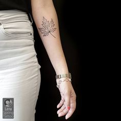 a woman's arm with a leaf tattoo on it