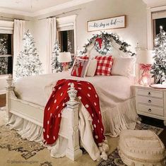 a bedroom decorated for christmas with red and white decorations on the bed, windows, and trees