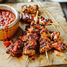 chicken skewers with marinara sauce and toothpicks on a cutting board