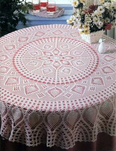 a table with a doily on top of it next to flowers and vases