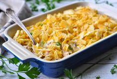 a casserole dish filled with chicken and noodles, garnished with parsley