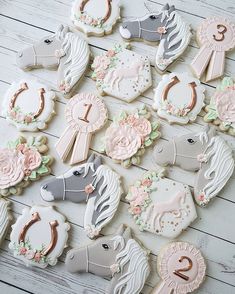 decorated cookies are arranged in the shape of horses and flowers on a white wooden table