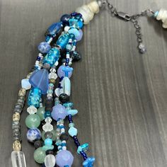 This necklace was designed to emulate ocean waves. I combined many many different beads to create this 6 strand necklace. In this necklace you will find czech glass, labradorite, ceramic beads, lapis, cultured sea glass, seed beads, sodalite, apatite, dragon vein agate, and many more. The ends of the necklace are ancient glass trade beads. The necklace is finished in sterling silver with a lobster clasp and extender chain.This necklace is adjustable from 20” to just under 22”.It weighs 145g. Unique Multi-strand Gemstone Beads, Blue Multi-strand Natural Stone Necklaces, Blue Multi-strand Natural Stone Necklace, Multi-strand Czech Glass Gemstone Beads Jewelry, Blue Multi-strand Czech Glass Jewelry, Multi-strand Czech Glass Jewelry With Gemstone Beads, Blue Multi-strand Necklace With Natural Stones, Blue Multi-strand Jewelry With Czech Glass, Unique Multi-strand Faceted Beaded Necklaces