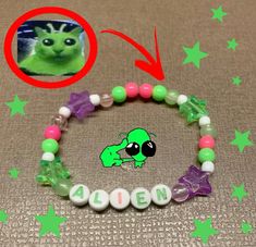 a bracelet with an image of a green alien on it and the word alien spelled out