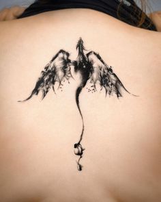 a woman's back with a tattoo design on her lower back and wings flying in the air