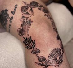 a woman's arm with flowers and leaves tattoo on her left side, while she is laying down