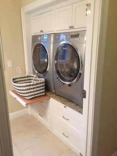 a washer and dryer sitting on top of each other in a room with white cabinets