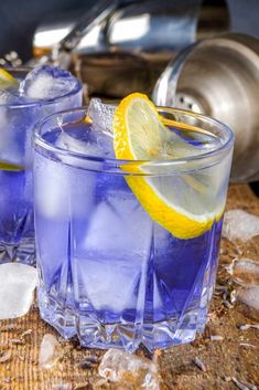 two glasses filled with blue liquid and lemon wedges