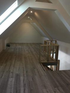 an empty loft with wooden floors and skylights