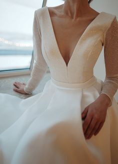 a woman in a white dress sitting on the floor with her hands behind her back