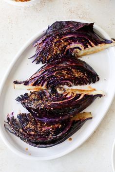 some red cabbage on a white plate next to other dishes and utensils in bowls