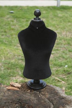 a black mannequin on top of a tree stump