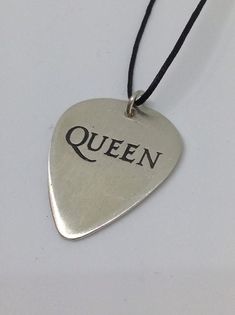 a guitar pick with the word queen written in black on it's back side