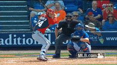 a baseball player swinging a bat on top of a field in front of a crowd