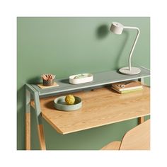 a desk with a lamp, bowl and plate on it next to a green wall