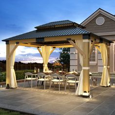 a gazebo with chairs and tables in front of a house