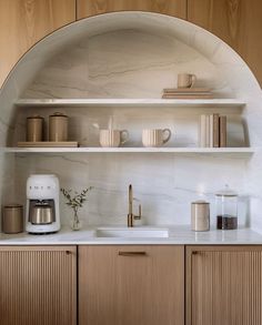 a kitchen with wooden cabinets and white counter tops, along with shelves filled with dishes