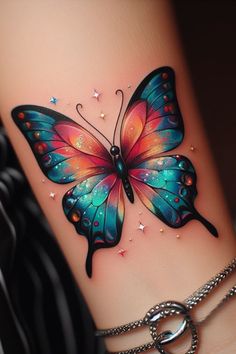 a colorful butterfly tattoo on the side of a woman's leg with chains around it