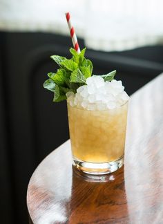 a drink with ice and mint on a wooden table