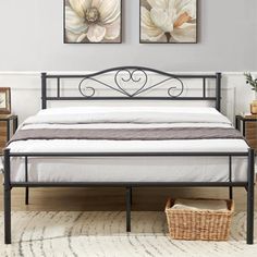 a bed with two paintings on the wall above it and a basket next to it