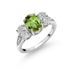 an oval cut peridot and diamond ring with three stones on the shoulders, set in white gold