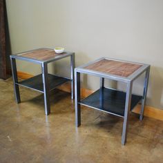 two small tables sitting next to each other on the floor in front of a wall