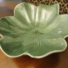 a green bowl sitting on top of a table next to a leopard print chair cushion