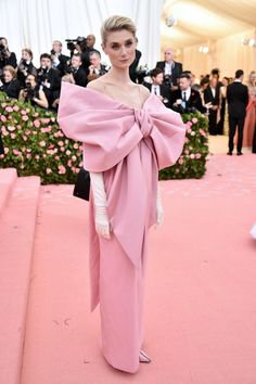 a woman in a pink gown standing on a pink carpet