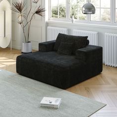 a living room with a black couch and white rug