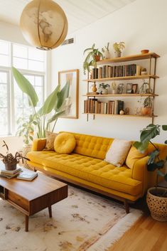 a living room with yellow couches and potted plants on the wall above them