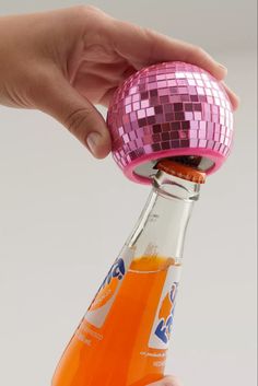 a person is holding a bottle with a disco ball on it and its lid open