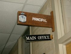 a sign that says principals and main office hanging from the side of a building in front of a door