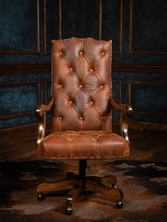 a brown leather office chair sitting on top of a wooden floor next to a wall