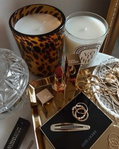 a table topped with candles and jewelry on top of a tray next to a mirror