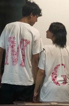 two people standing next to each other in front of a mirror with the word love on it