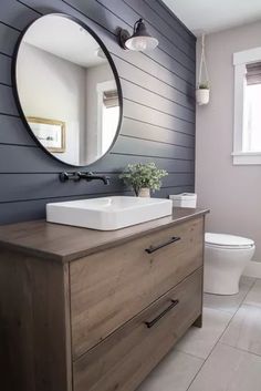 a white sink sitting on top of a wooden dresser next to a toilet in a bathroom