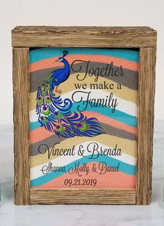 a wooden frame with a colorful peacock on it and two bottles next to it that say, together we make a family