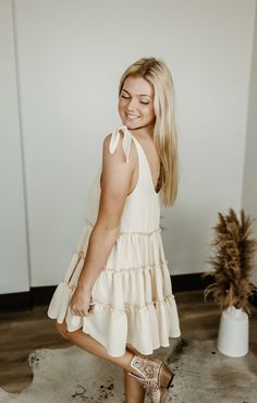 Step into carefree vibes with the Sundown Serenade Tiered Babydoll Dress. Made from textured crepe fabric, this boho-inspired dress features tiered ruffles for a playful, flowy silhouette that dances with every step. The adjustable tie straps allow for a customizable fit, making it perfect for sunny beach days or warm nights out. With its wide bottom sweep, this dress adds an effortlessly feminine touch to any occasion. Whether you're strolling through a farmers' market or heading to a casual su Flowy Summer Tiered Dress For Day Out, Flowy Tiered Summer Dress For Day Out, Flowy Tiered Dress For A Summer Day Out, Cute Vacation Dresses With Ruffles, Cute Vacation Dress With Ruffles, Feminine Ruffled Sundress For Vacation, Beige Ruffled Sundress For The Beach, Beige Ruffled Sundress For Beach, Cute Flowy Ruffle Dress For Summer