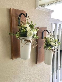 two vases with flowers are hanging on the wall