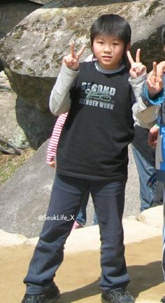 two young boys standing next to each other with their hands in the air and making peace signs