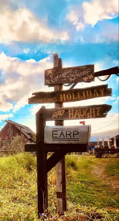 a wooden sign sitting on the side of a lush green field